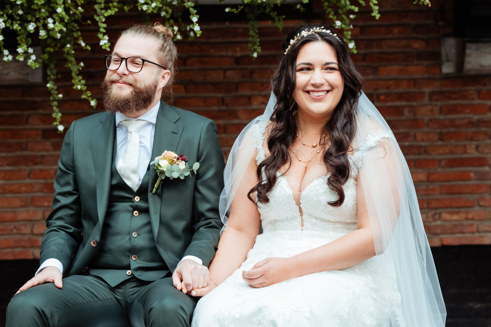 Bruidspaar poseert bij een bakstenen muur in Tilburg