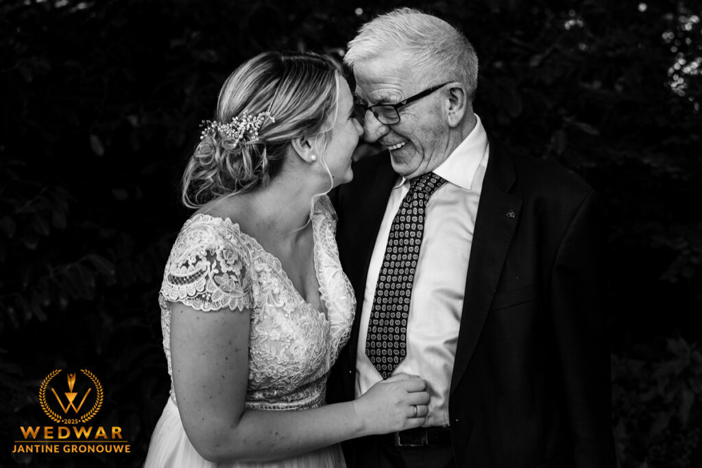 Zwart-witfoto: de bruid en haar opa lachen naar elkaar, hoofden dicht bij elkaar. Wedwar Award.