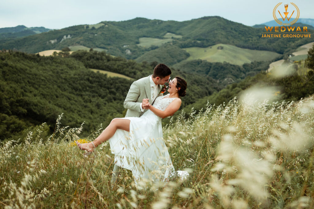 Bruidspaar in een dipkiss op een heuvel met uitzicht over de groene heuvels van Le Marche, Italië. Wedwar Award.